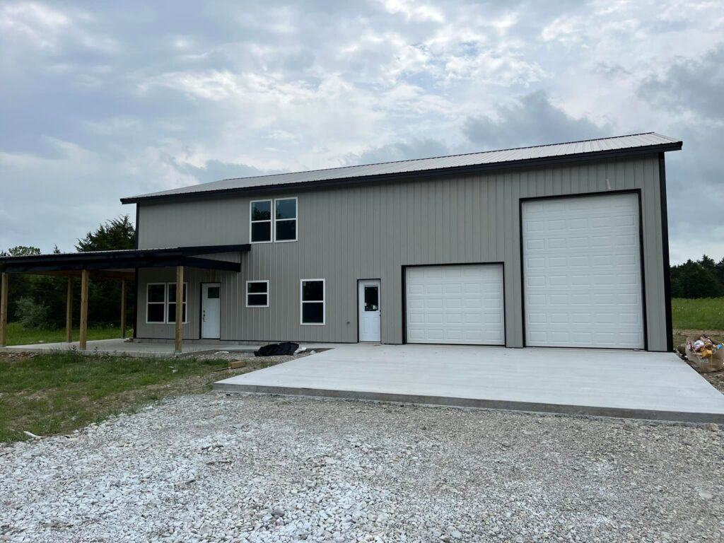 two story metal home with tall garage doors