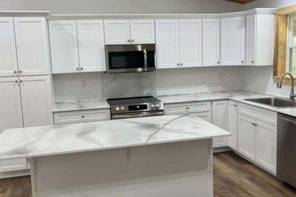 spacious kitchen with island and white cabinets and countertops